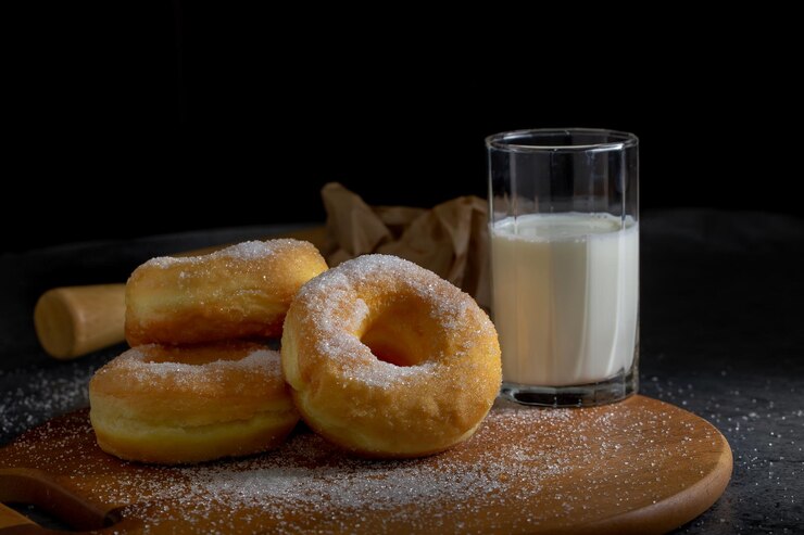 Photo des beignets avec du sucre sur une assiette en bois sur un fond de table sombre
