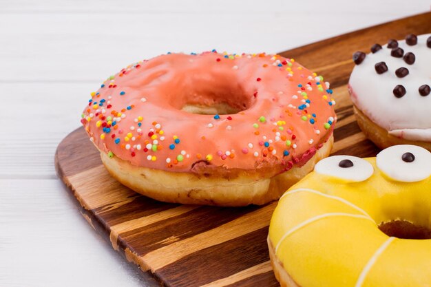 Beignets fraîchement cuits sur fond de bois. Gâteaux glacés sucrés sur une planche à découper en gros plan.