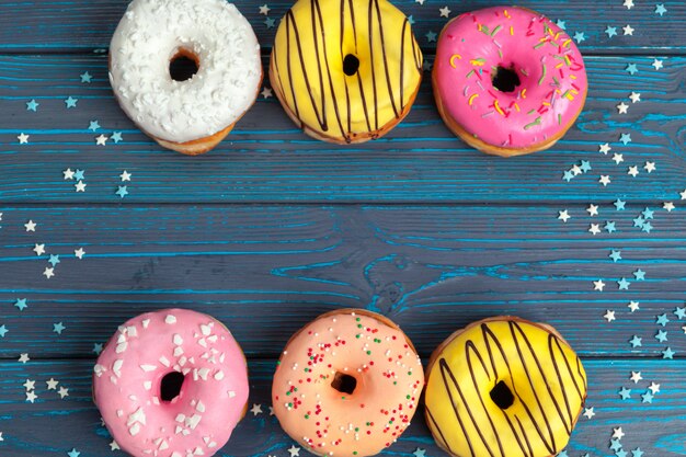 Beignets frais colorés sur une surface en bois bleu foncé