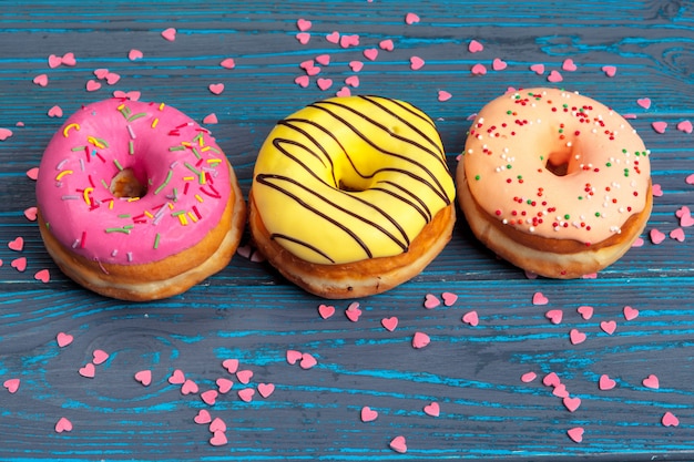 Beignets frais colorés sur la surface en bois bleu foncé