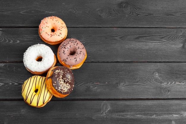 Beignets frais colorés sur une surface en bois noir foncé