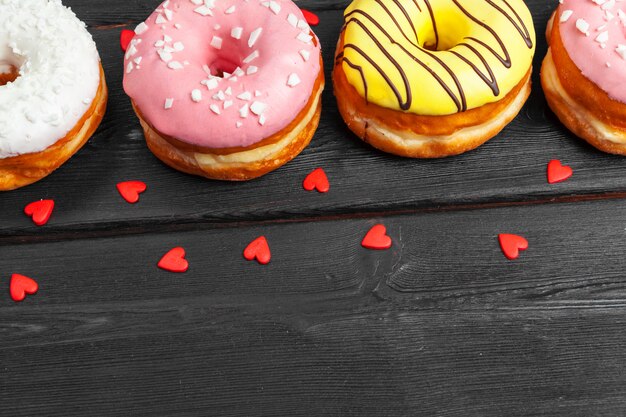 Beignets frais colorés sur une surface en bois noire foncée