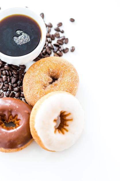 Beignets frais avec du café sur fond blanc.