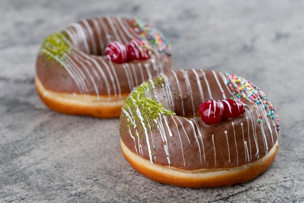 Beignets glacés au chocolat décorés de paillettes et de baies sur fond de pierre.