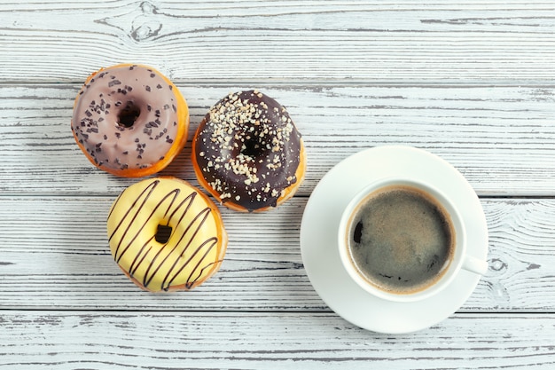 Beignets glacés sur une surface en bois avec une tasse de café