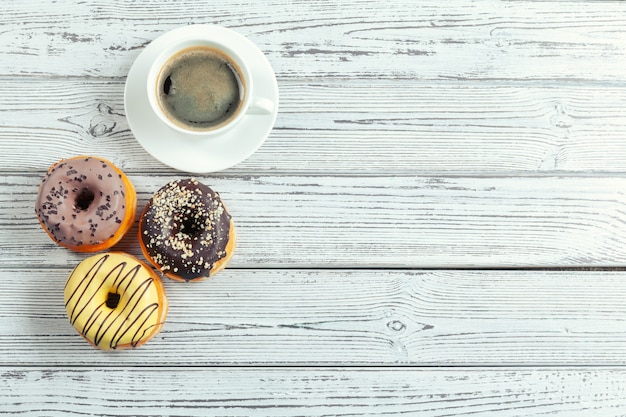 Beignets glacés sur une surface en bois avec une tasse de café