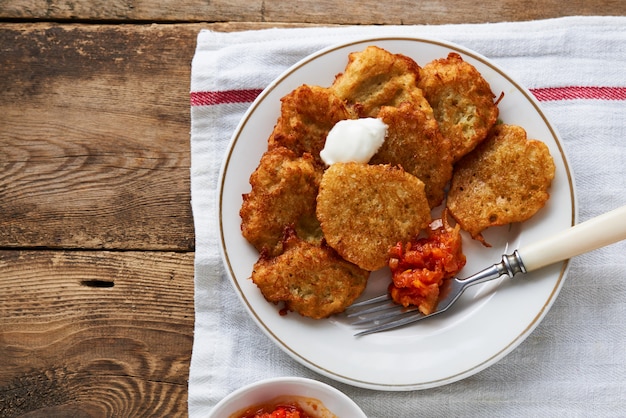 Beignets de pommes de terre avec crème sure et sauce tomate sur table en bois