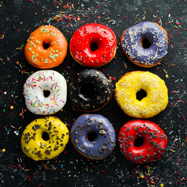 Beignets sucrés colorés sur fond de pierre noire Vue de dessus Mise à plat