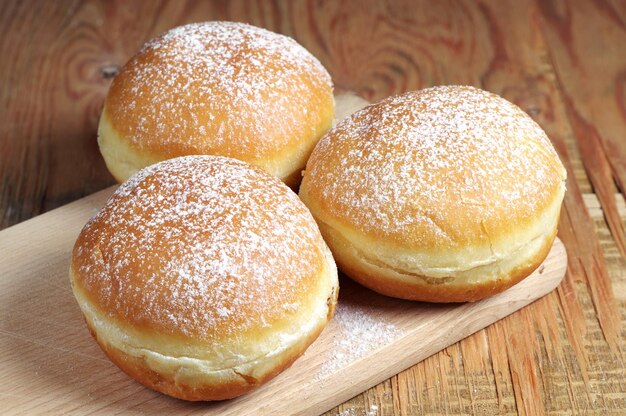 Beignets sucrés saupoudrés de sucre en poudre sur table en bois