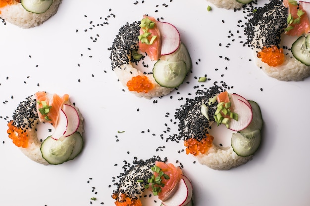 Beignets de sushi au saumon, concombre et radis sur vue de dessus blanc