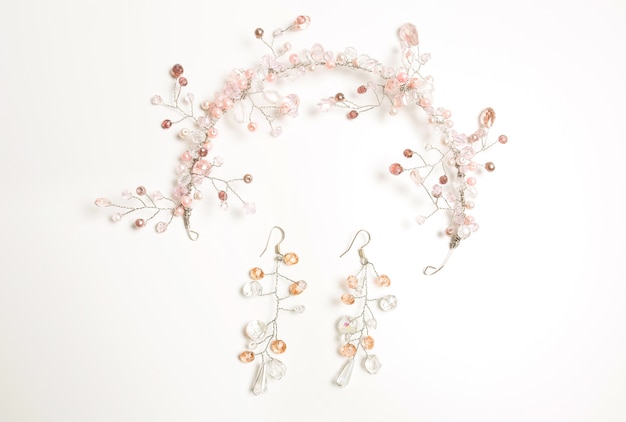 Bel accessoire pour cheveux et boucles d'oreilles décorés de perles blanches et roses sur fond blanc