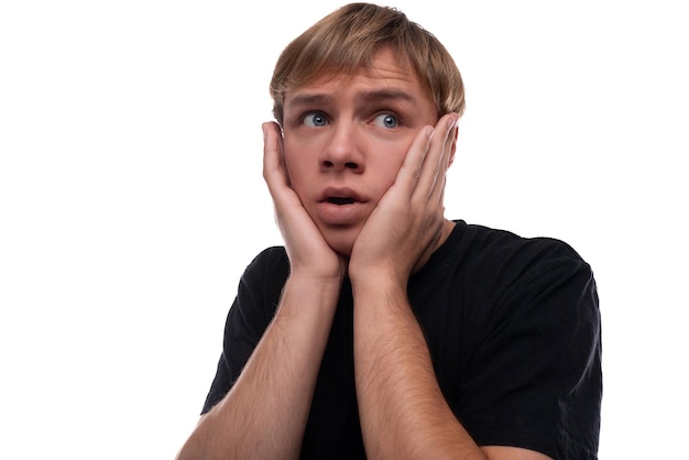 Un bel adolescent blond blanc en t-shirt noir est inquiet et veut se cacher