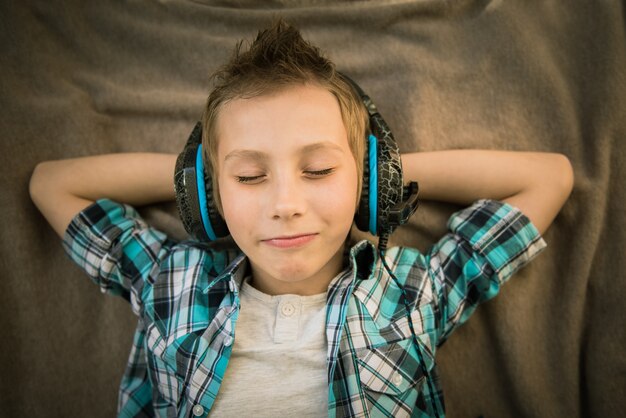 Bel adolescent pose et écoute de la musique avec des écouteurs