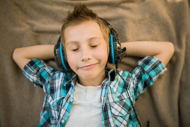 Bel adolescent pose et écoute de la musique avec des écouteurs