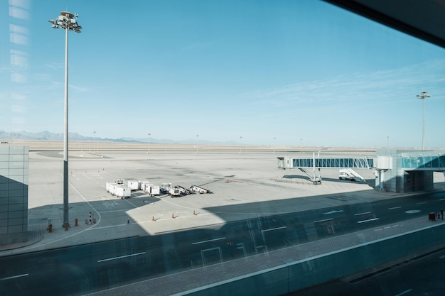Bel aéroport avec des voitures, une passerelle d'embarquement et une piste vide sur fond de montagnes, de désert et de ciel bleu. Concept de voyage en avion. Pandémie et compagnies aériennes