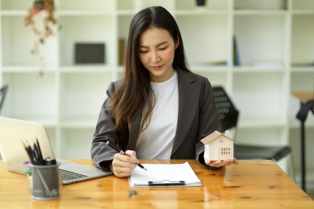 Bel agent immobilier asiatique travaillant au bureau, examinant le contrat de location sur papier. Consultant immobilier travaillant dans un bureau moderne.