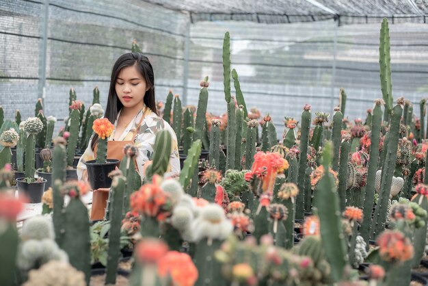 Bel agriculteur vérifiant la qualité des plantes de cactus avec tablette sur le pot à la ferme de cactus.