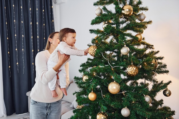 Avec un bel arbre Mère avec sa petite fille est à l'intérieur à la maison ensemble