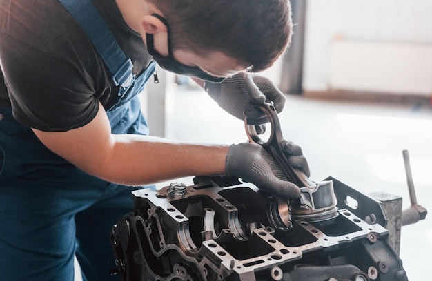 Bel éclairage. Réparateur professionnel en masque de protection noir fonctionne avec un moteur automobile cassé