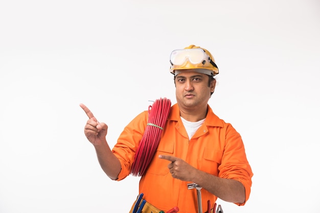 Bel électricien ou ingénieur asiatique indien en action avec un chapeau de sécurité jaune isolé