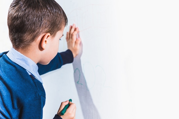 Le bel enfant dessine sur le mur avec des crayons colorés