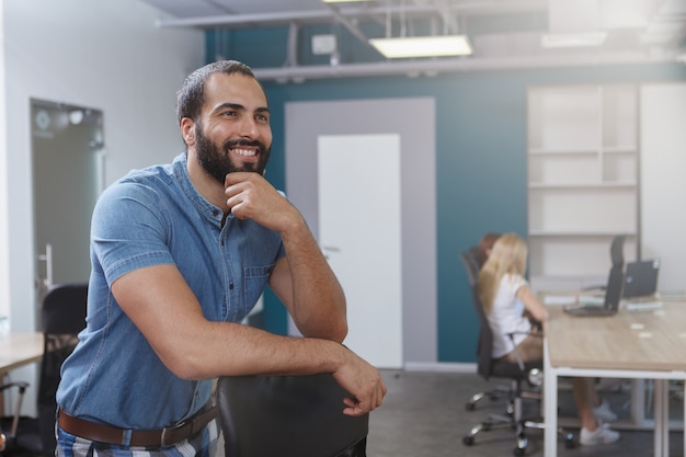 Bel entrepreneur de sexe masculin barbu regardant ailleurs rêveusement