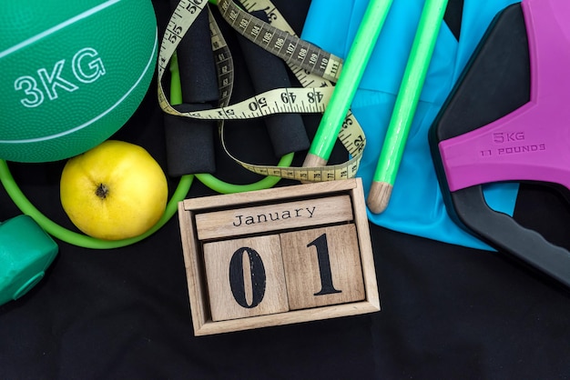 Bel équipement sportif avec une horloge en bois le 1er janvier sur un fond noir spacieux Le concept de nouvelle vie