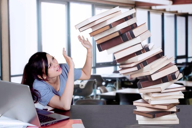 Un bel étudiant tient des livres qui tombent