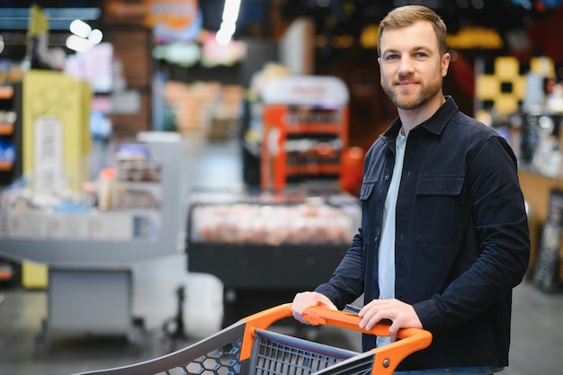 Bel homme achetant des aliments et des boissons sains dans un supermarché ou une épicerie moderne Concept de style de vie et de consommation