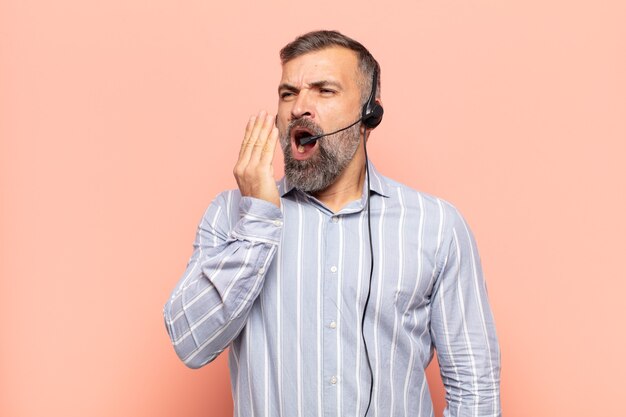 Bel homme adulte bâillant paresseusement tôt le matin, se réveillant et à la somnolence, fatiguée et ennuyée