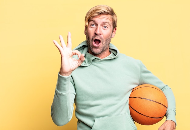 bel homme adulte blond avec un ballon de basket