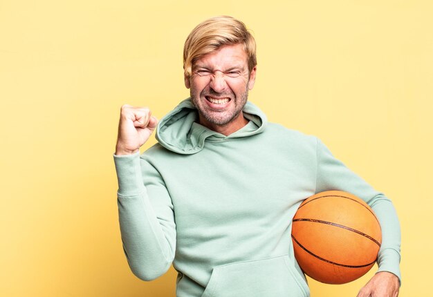 Bel homme adulte blond avec un ballon de basket