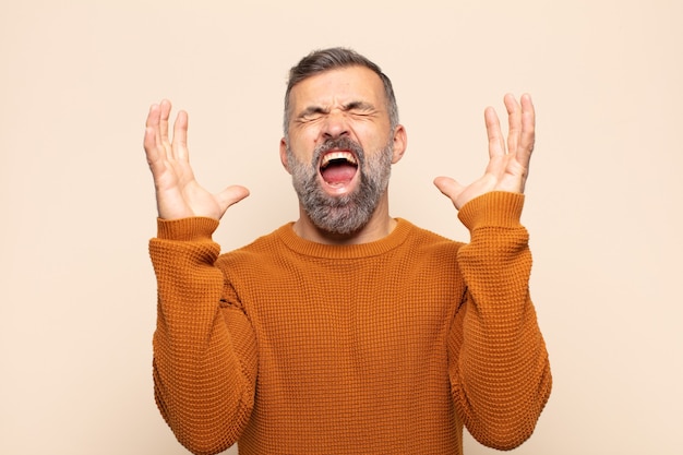 Bel homme adulte hurlant furieusement, se sentant stressé et agacé avec les mains en l'air en disant pourquoi moi