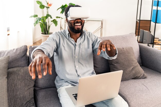 Bel homme adulte noir à la maison jouant avec un casque vr