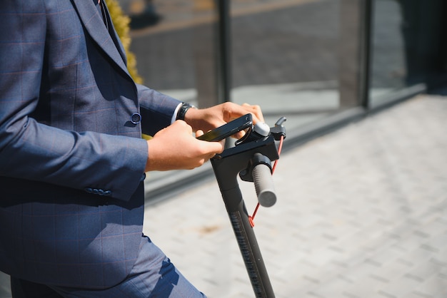 Photo bel homme d'affaires africain équitation scooter électrique à l'extérieur