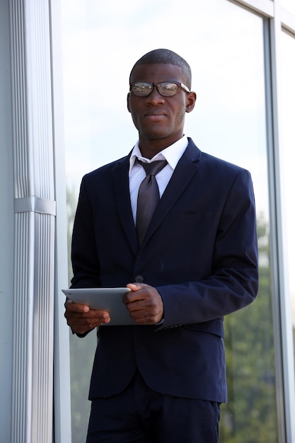 Photo bel homme d'affaires afro-américain avec tablette numérique près du centre d'affaires