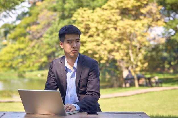 Bel homme d'affaires asiatique à l'aide d'un ordinateur portable