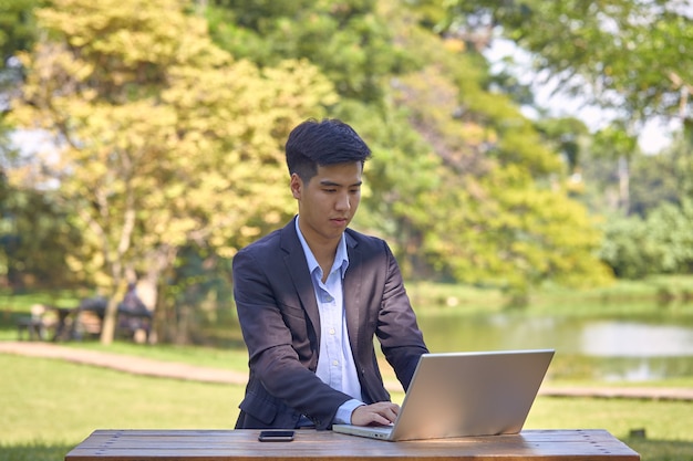 Bel homme d'affaires asiatique à l'aide d'un ordinateur portable