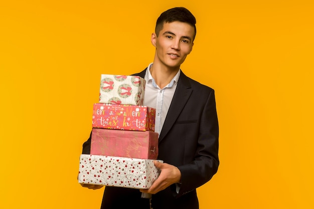 Bel homme d'affaires asiatique tenant une boîte-cadeau sur une image de fond jaune