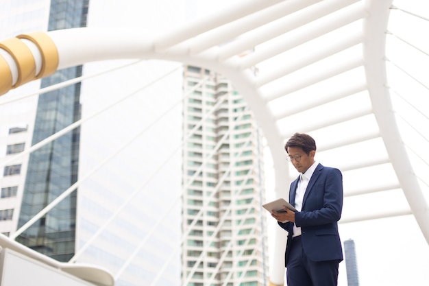 Bel homme d'affaires asiatique travaillant à l'extérieur avec une tablette numérique à l'extérieur.