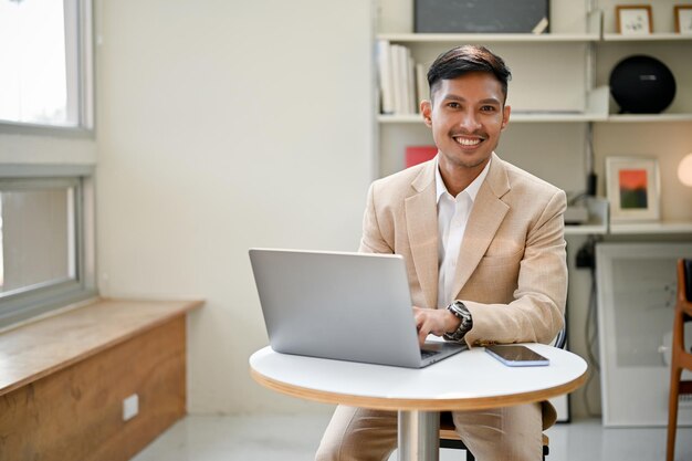 Bel homme d'affaires asiatique utilisant son ordinateur portable et travaillant à distance dans un café