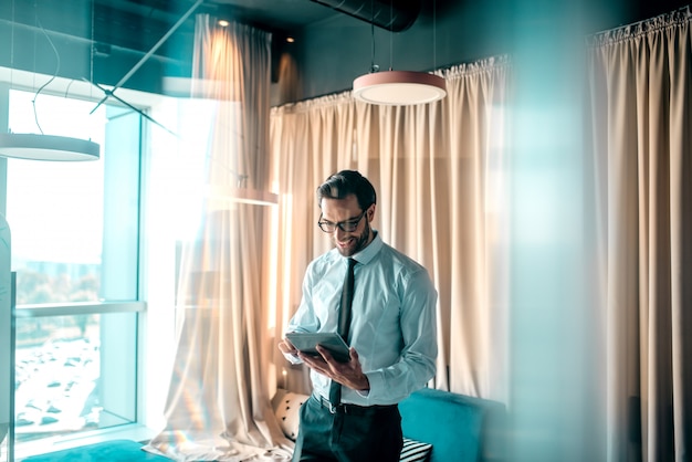 Bel homme d'affaires au bureau en regardant la tablette.