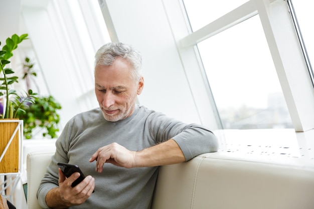 un bel homme d'affaires barbu aux cheveux gris senior mature s'asseoir dans un café à l'aide d'un téléphone portable.