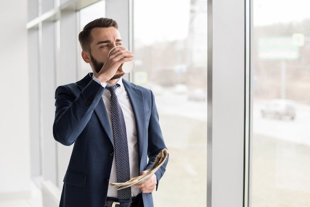 Bel homme d'affaires, boire du café par la fenêtre