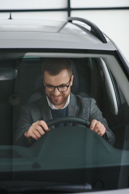 Bel homme d'affaires conduisant une voiture avant d'acheter