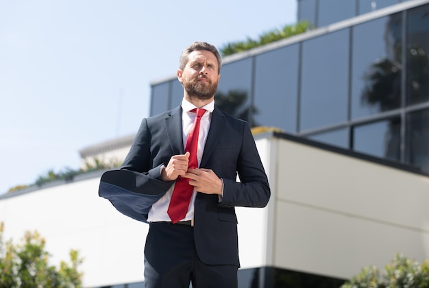 Bel homme d'affaires en costume et cravate rouge en plein air, entrepreneur.