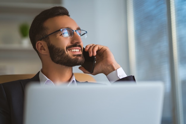 Le bel homme d'affaires dans un téléphone à lunettes