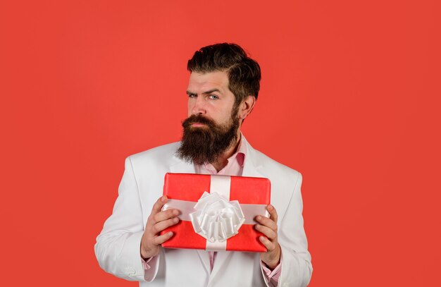 Bel homme d'affaires détient une boîte-cadeau saint valentin noël nouvel an anniversaire et concept de vacances