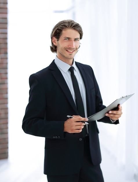 Bel homme d'affaires avec document commercial debout au bureau