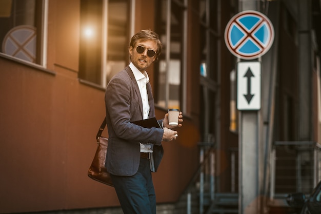 Bel homme d'affaires lokking sur le côté alors qu'il traversait une route.